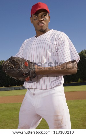 Young baseball pitcher standing on field and looking away