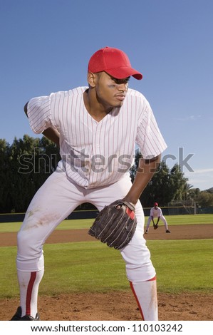 Young baseball pitcher playing on field with team mate in the background