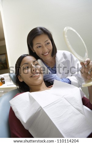 Female dentist and patient looking in mirror while treatment