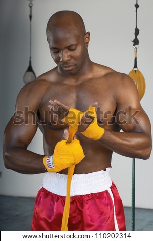 African American boxer wrapping bandage while preparing himself for a match