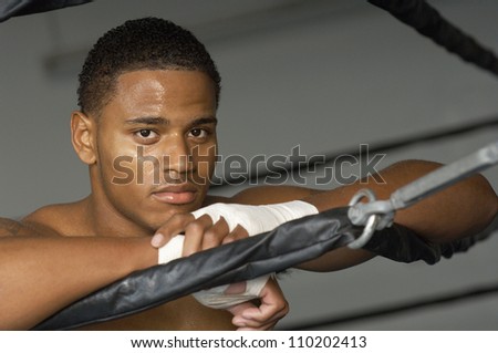 Portrait of an African American boxer with wrapped hands resting on boxing ring