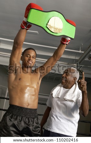 African American boxer holding championship belt with coach