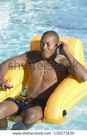 Young African American man listening music in swimming pool