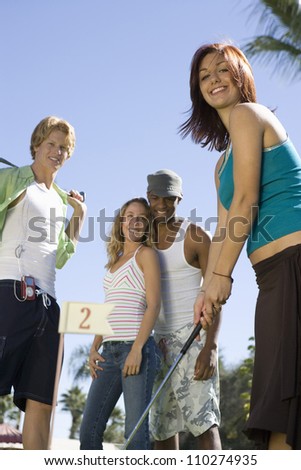 Young woman playing golf with friends