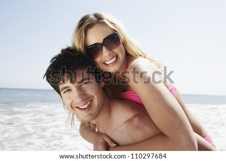 Portrait of happy man carrying woman on beach