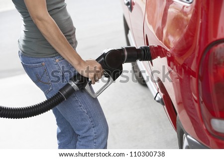 Lower body of a woman refueling her car