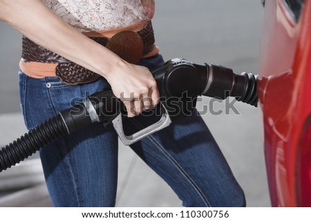 Lower body of a woman refueling a car