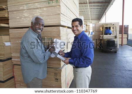 Happy warehouse workers holding clipboards