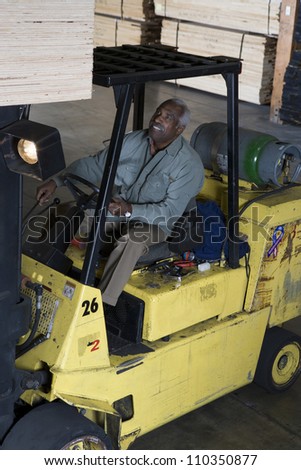 African American senior man driving forklift