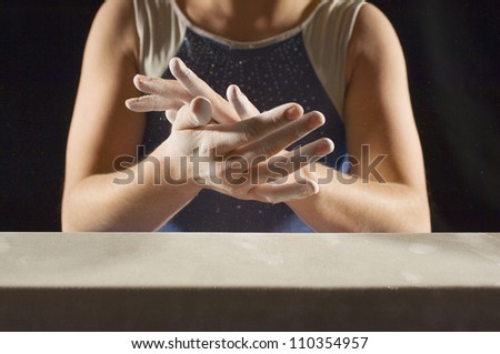 Midsection of a female gymnast applying white powder to hands