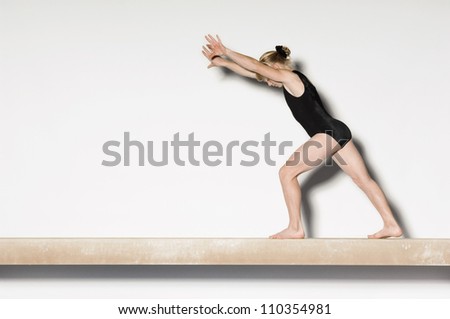 Young female on balance beam preparing to do handstand