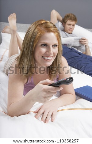 Happy woman watching TV in bedroom
