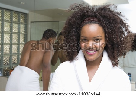 Closeup of an African American woman in bathrobe with man in background