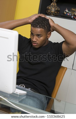 Worried young African American man looking at computer