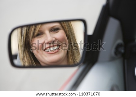 Reflection of woman in side view mirror of car