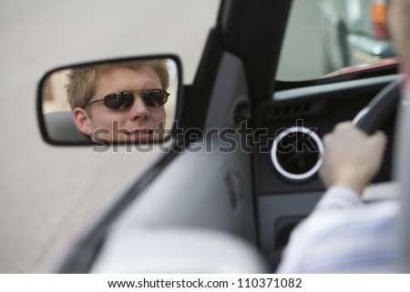 Reflection of young man in side view mirror of car