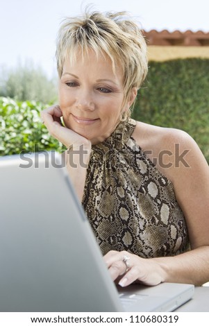 Portrait of a happy middle aged woman using laptop