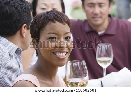 Portrait of happy African American woman with friends holding wine glass