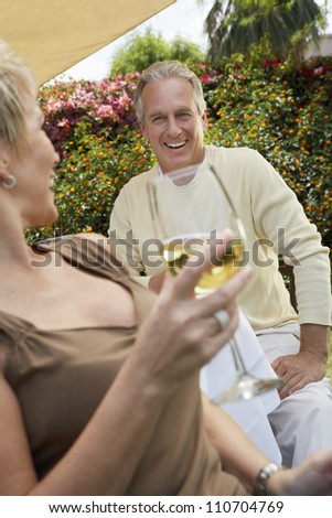 Happy middle aged woman with man holding glass of wine