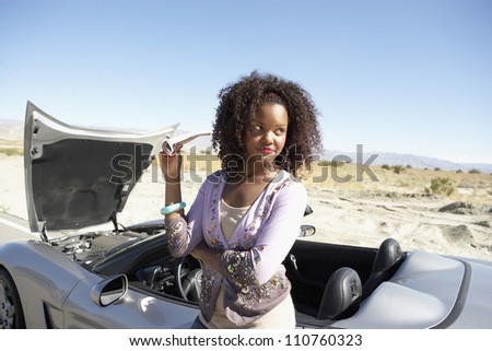 Young African American woman standing by car and looking for help