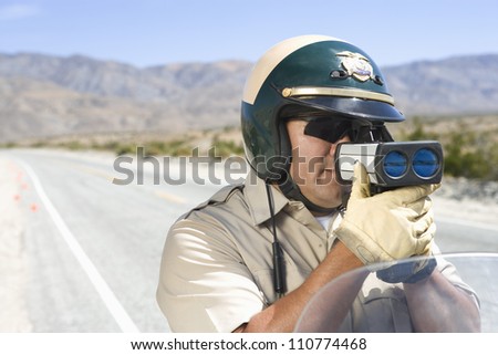 Middle aged traffic officer looking through radar gun