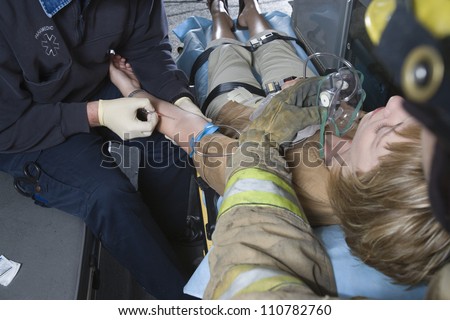 Firefighter and EMT doctor helping an injured patient in ambulance