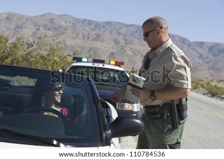 Traffic officer checking woman\'s license with mountain range in the background
