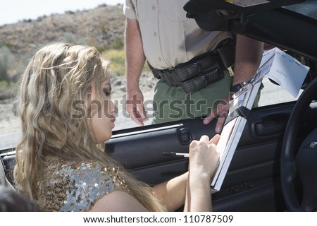 Beautiful young woman writing on traffic ticket with traffic cop standing by her car