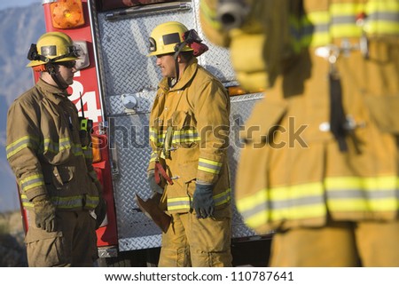 Male firefighters talking with each other with colleague in the foreground