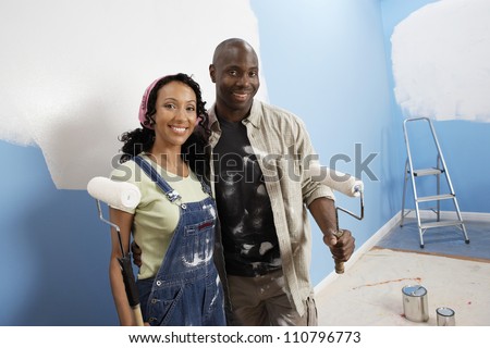 Portrait of happy African American couple painting their new house