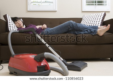 Woman Relaxing On Couch With Vacuum Cleaner