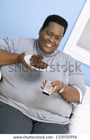 African American man eating donut while watching television