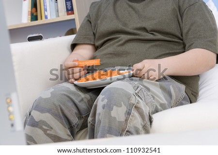 Mid section of teenage boy with plate of carrot sticks