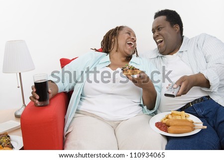 Obese African American couple sitting together with plates of junk food