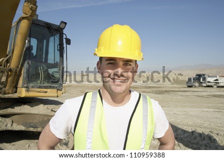 Portrait of a worker wearing hardhat in front of a crane at construction site