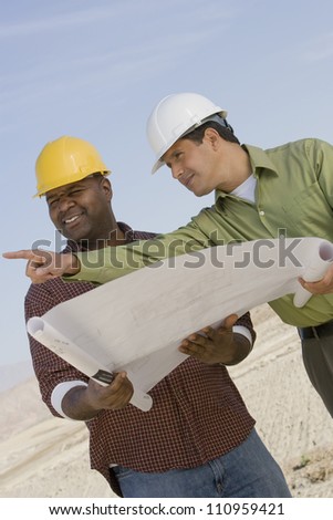 Portrait of an builder and supervisor holding blueprint at construction site