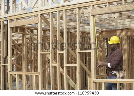 Side view of a worker measuring form work at construction site