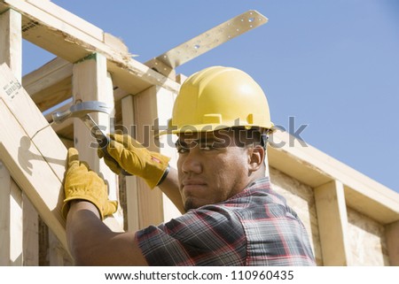 Man using a hammer to nail a wood at construction site