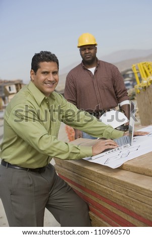 Architect and builder discussing with laptop at construction site