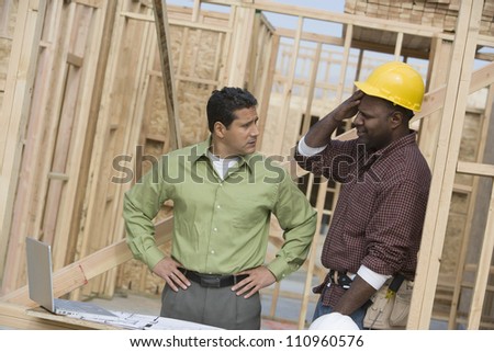 Architect and builder discussing with laptop at construction site