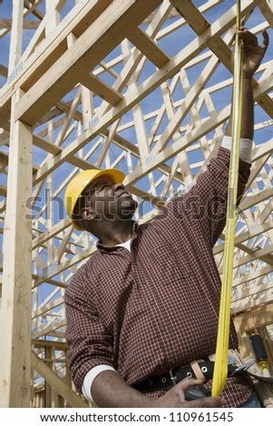 Young african american worker measuring form work at construction site