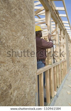 Full-length of a worker measuring form work at construction site