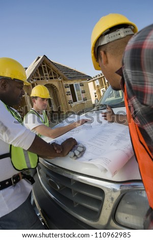 Team of workers discussing over a blueprint