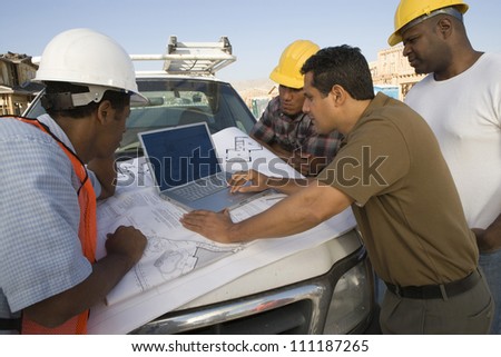 Architect and builders discussing with laptop