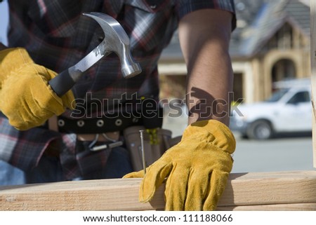 Close-up of builder\'s hands hammering a nail into wood