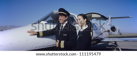 Pilot standing with stewardess in front of an aircraft