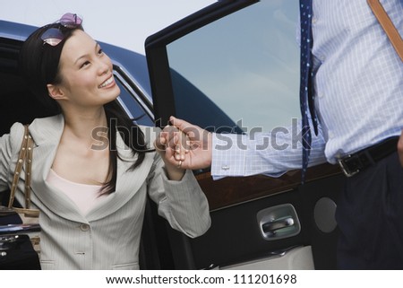 Businessman helping businesswoman to get down from car at the airport
