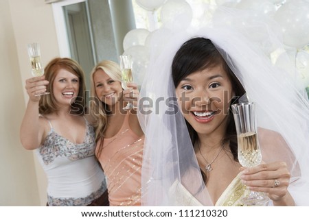 Portrait of bride and friends holding champagne flute at party
