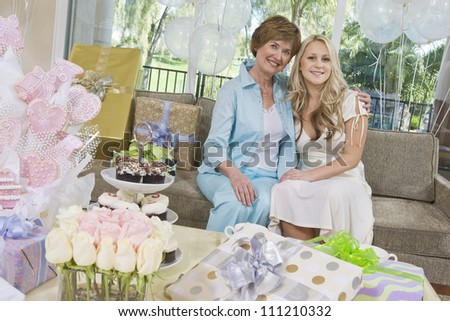 Portrait of mother and daughter sitting on sofa at party