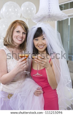 Portrait of bride and her friend holding juice glasses at party
